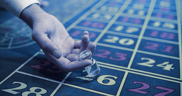 a dealer about to place a live roulette win marker on the number 26