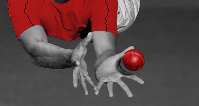a fielder in a red shirt attempts to catch a cricket ball