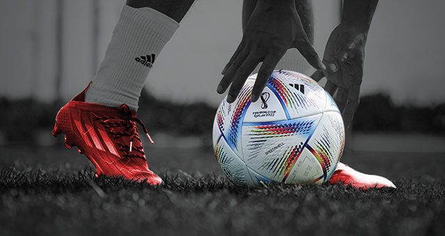 footballer with red shoes having just placed down the official 2022 World Cup football