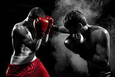 a boxing match where one fighter with red shorts and gloves defends against a punch from another fighter with black gloves and shorts
