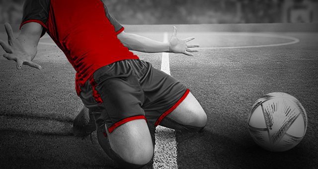 ein Fußballspieler, der mit dem WM-Ball neben sich feiert