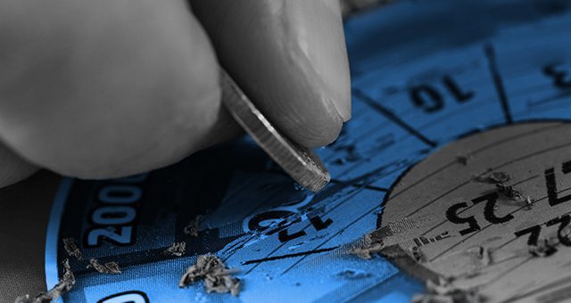 a blue scratchcard being scratched at by a person with a grey coin